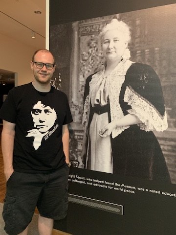 Randall Olson beside an exhibition portrait at a foundation program